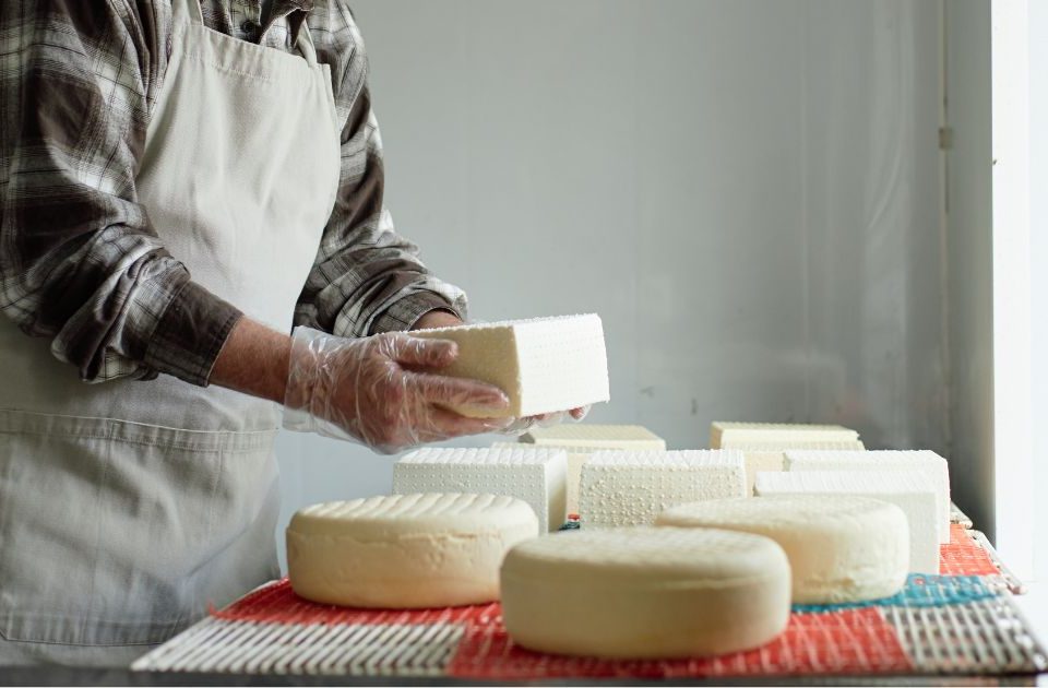 Persona adulta con varios quesos delante en Gran Canaria de Quesos Bolaños